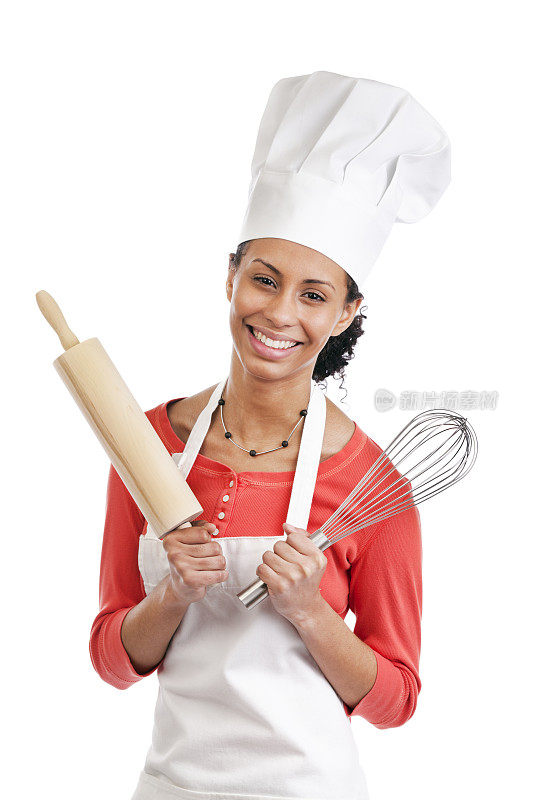 快乐的年轻女人厨师穿着围裙和厨师帽