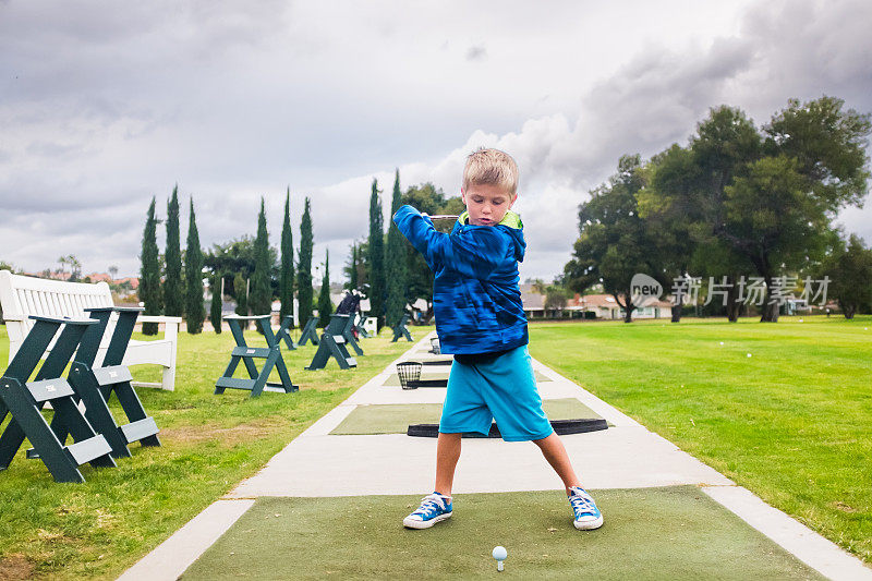 小男孩在练习场打高尔夫球