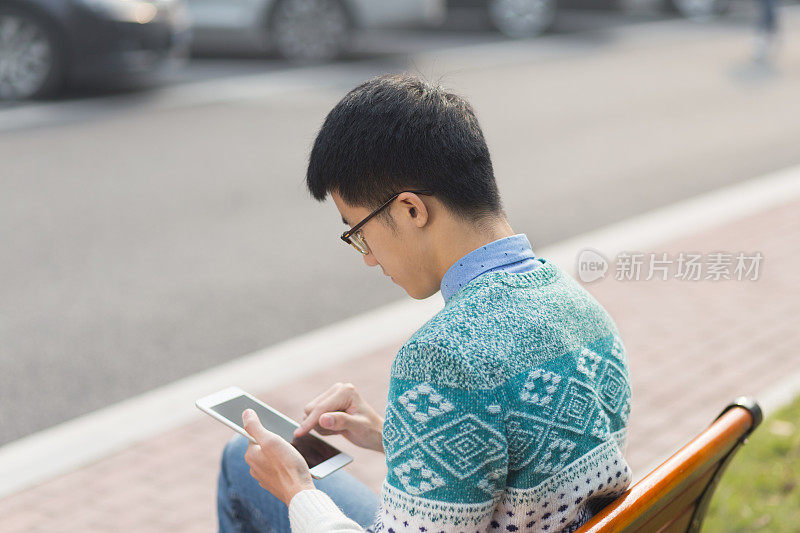 年轻的亚洲男学生拿着平板电脑