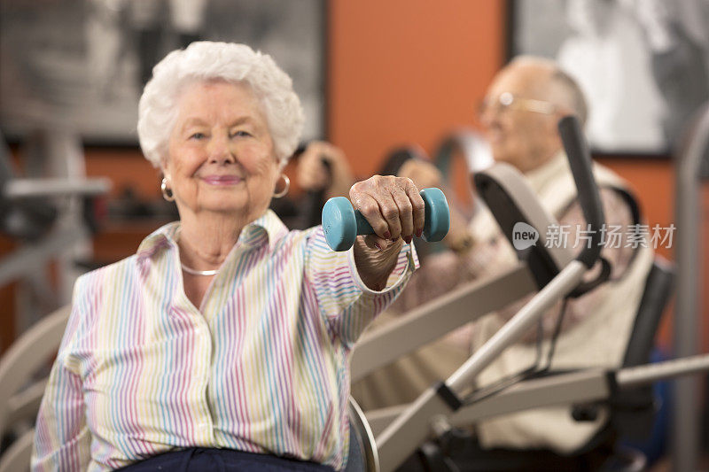老年女子在健身房举重，注重体重
