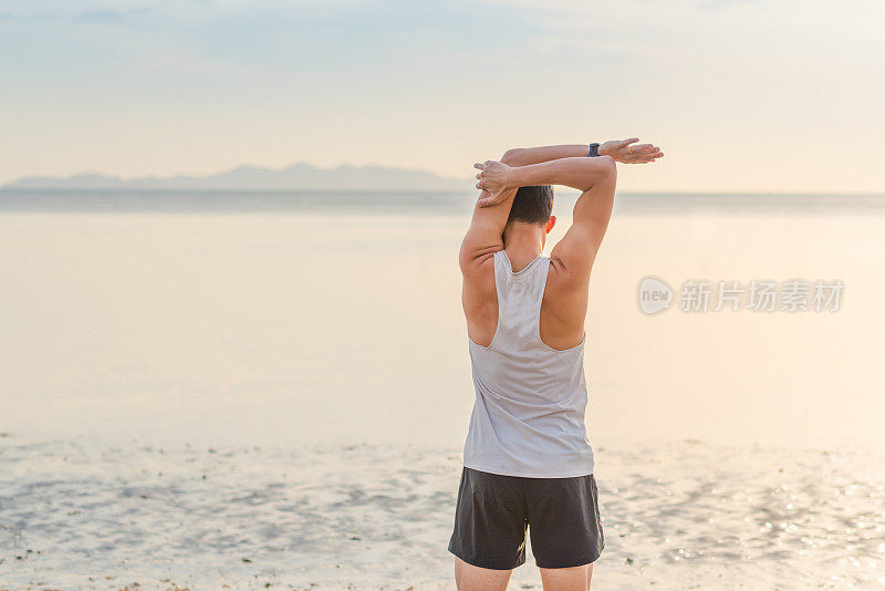 年轻的亚洲男子在日落海滩做瑜伽运动