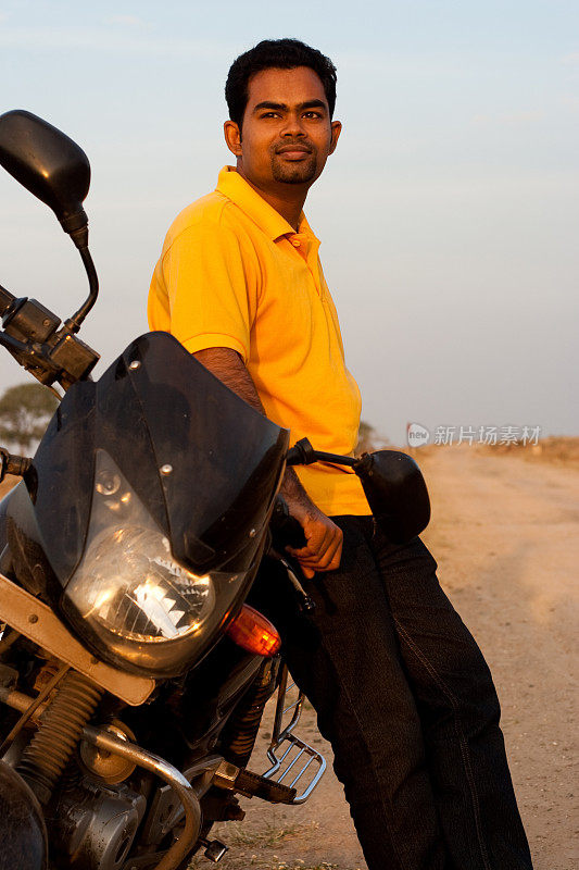 聪明的印度年轻人在乡村道路上骑自行车