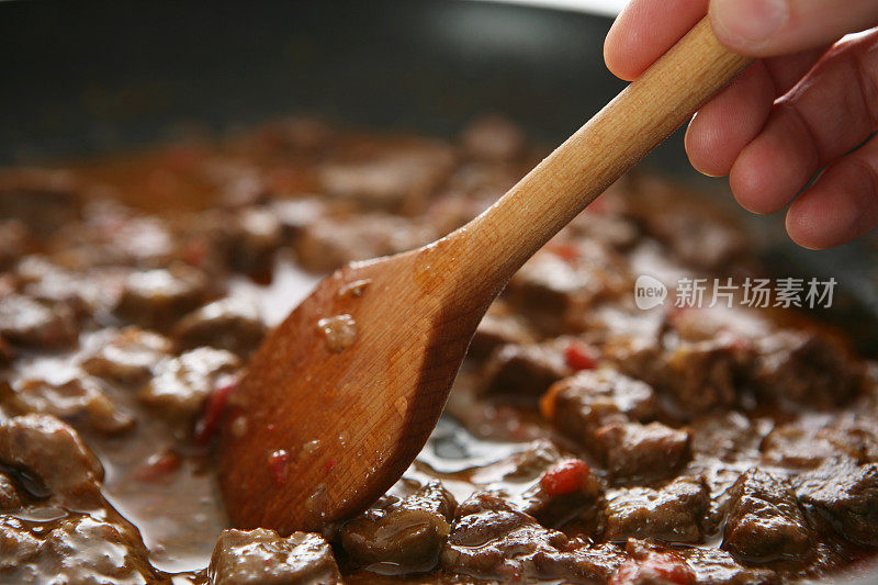 用木勺在平底锅里煮晚餐的特写