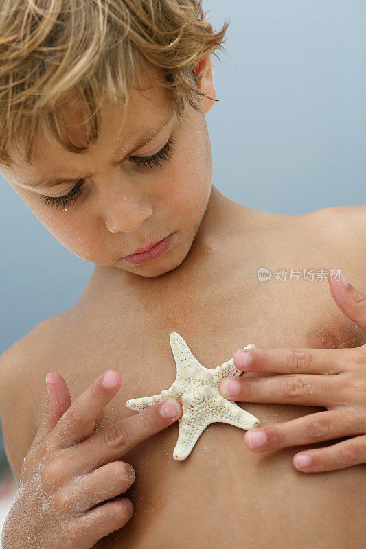 在海滩上抱着海星的男孩