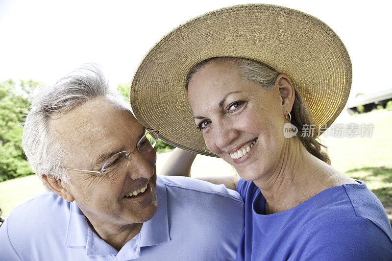 一个男人对着他戴着帽子的妻子微笑，而她正对着镜头微笑。