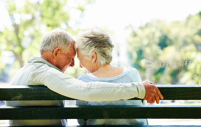 年长的男人和女人坐在户外的长椅上