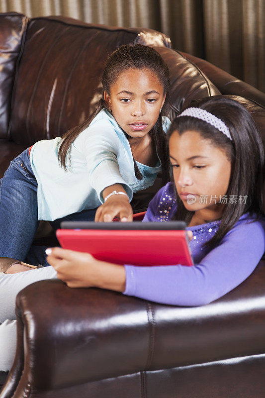 非裔美国女孩在沙发上用平板电脑