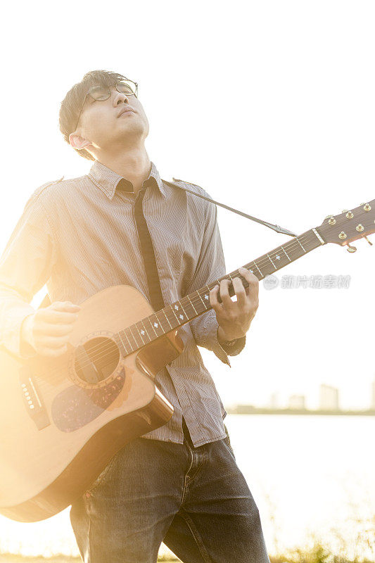 年轻男子在夕阳下弹奏吉他