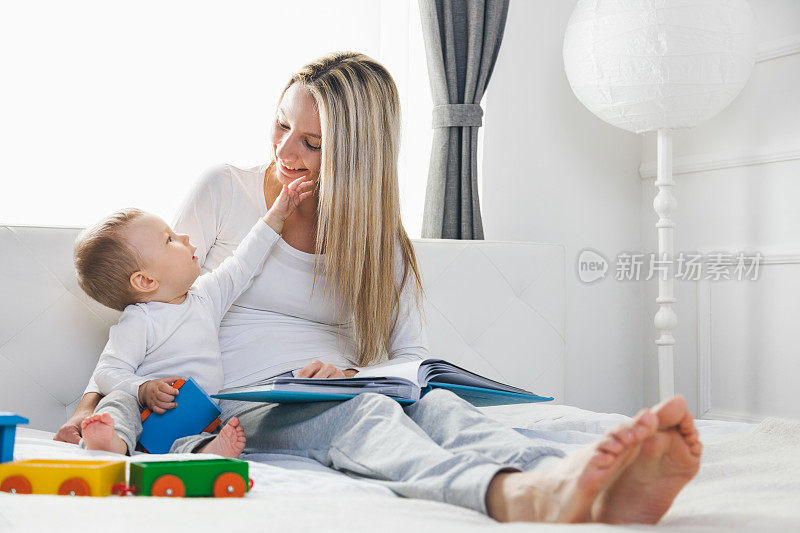孩子的教育。快乐的妈妈和她的孩子坐在床上看书