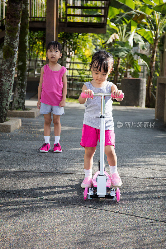 亚洲小中国女孩争着玩滑板车