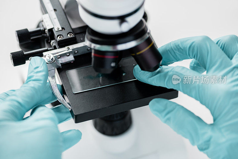 科学家在实验室使用显微镜和玻璃显微镜载玻片工作的剪影