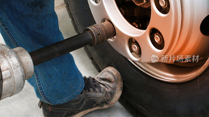 亚洲人机械师在车间里给一辆汽车换轮子。