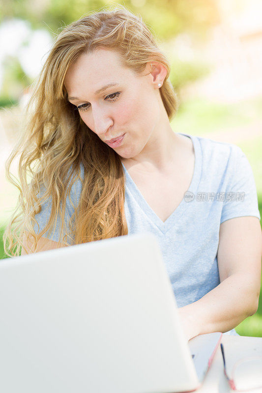 年轻的成年女性在户外用笔记本电脑视频聊天。