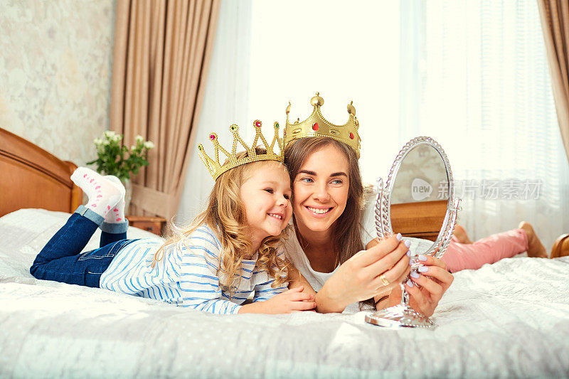母亲和女儿戴着皇冠在屋顶上玩镜子