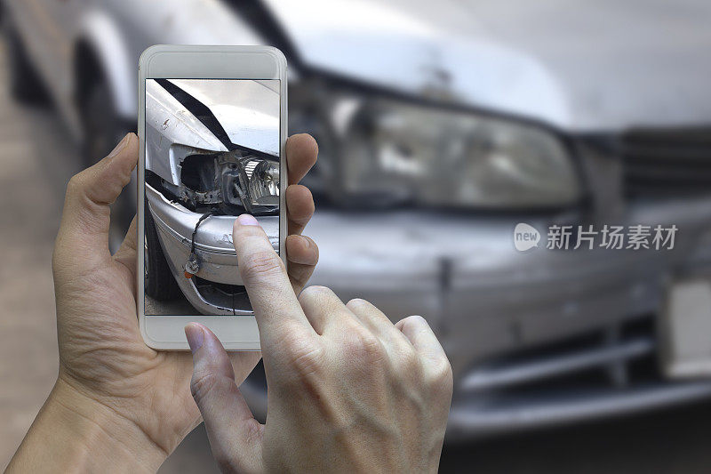 手持智能手机在车祸现场拍照，为车祸投保