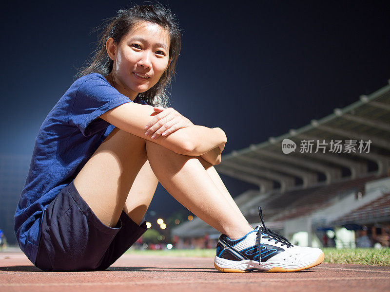 亚洲女孩晚上在体育馆慢跑后休息。