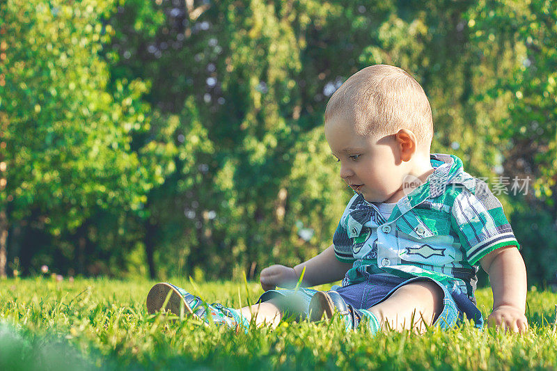 小婴儿独自坐在公园的草地上玩耍。