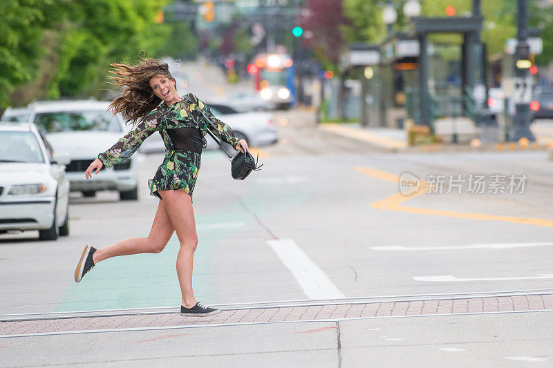 年轻女子在美国斑马线上过马路，跳着