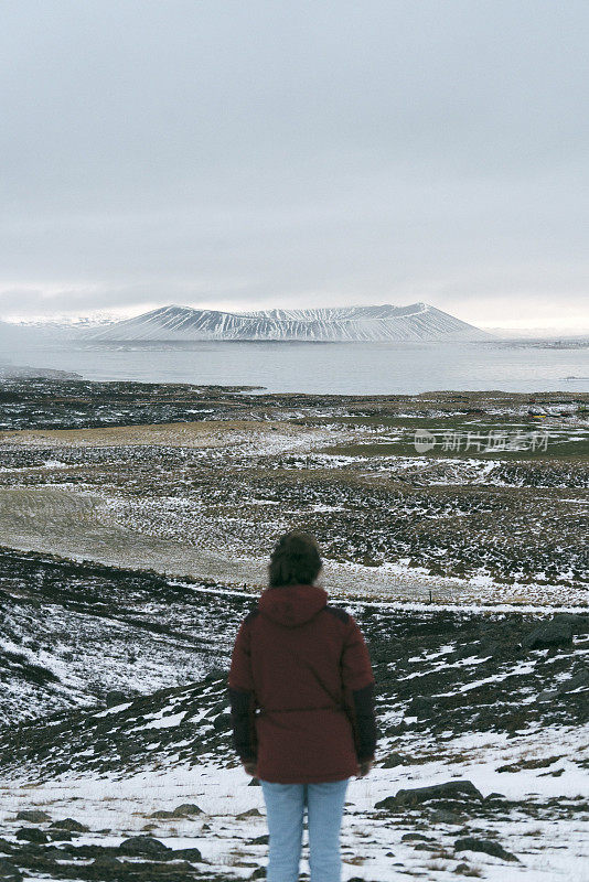 女人看风景的火山附近的Myvatn湖在冬天