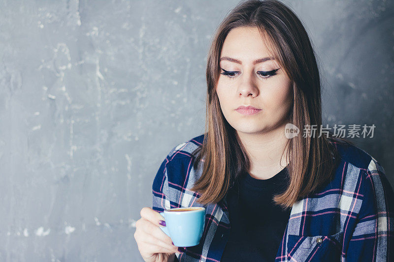 年轻的白人妇女捧着一杯咖啡享受在自由时间的肖像。