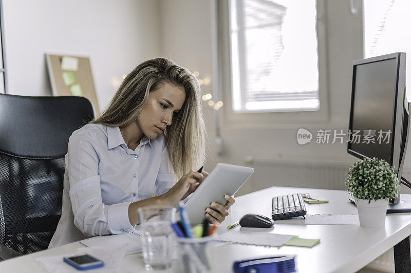 年轻的女商人在办公室里使用平板电脑