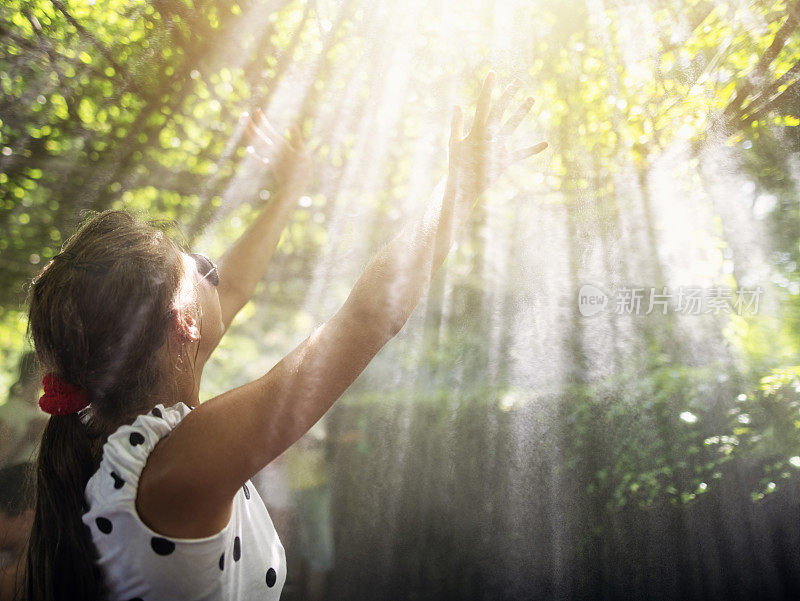少女在洒水器的水雾中寻求上帝的光芒