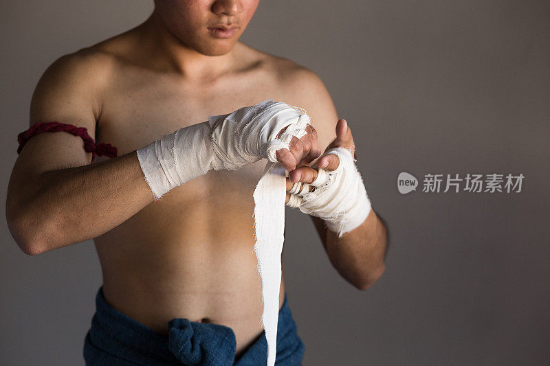 年轻的亚洲拳击手或泰拳战士准备和包裹他的手与拳击包装前训练或战斗，泰拳和武术概念