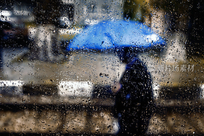 雨落在玻璃上，和拿着蓝伞的男人