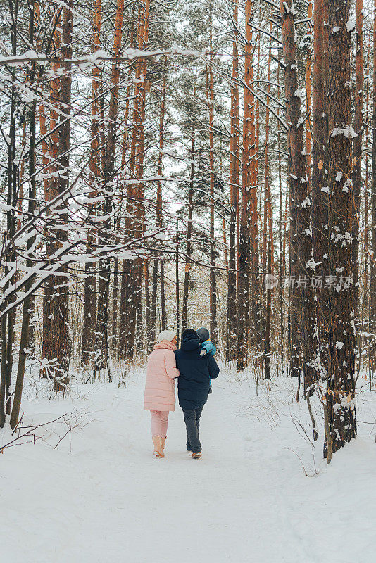 带着孩子的步行家庭。冬天一家人在大自然中散步。冬天一家人在大自然中散步。很多雪。