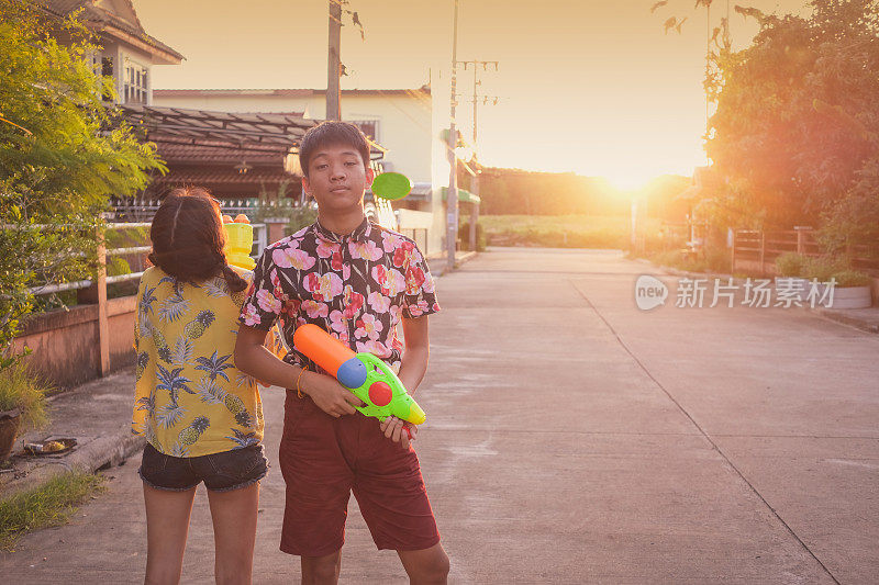 在泰国泼水节上，男孩和女孩在夕阳下一起玩水枪