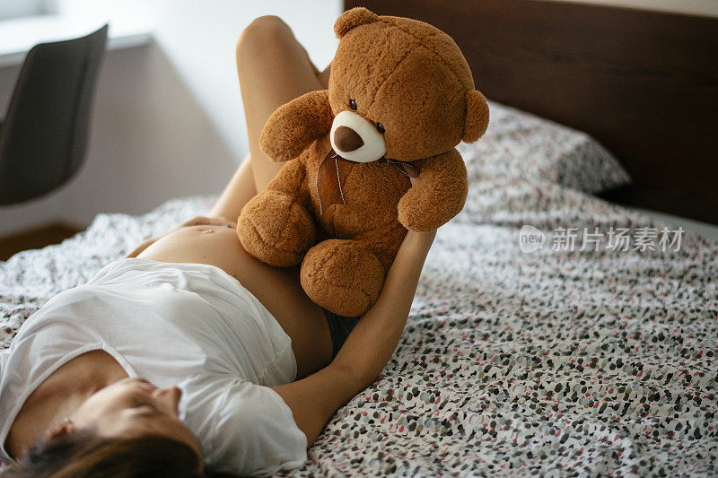 快乐的孕妇抱着泰迪熊