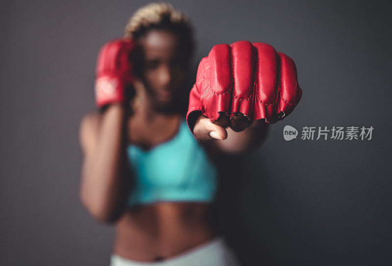 女斗士的拳头靠近。直接聚焦在手套与图像的其余部分模糊。关于运动和人的概念