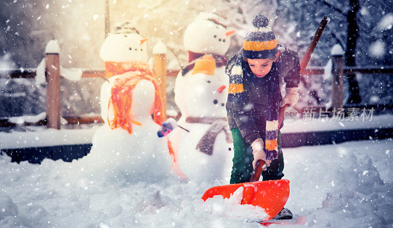 小男孩用铁锹清理雪道