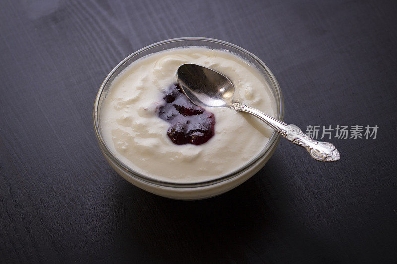自制的果酱酸奶装在玻璃碗里，放在深黑色的桌子上