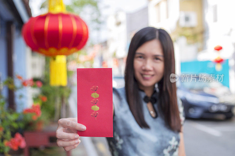 春节快乐。一位穿着旗袍的美丽中国女子给你一个红包或红色礼券