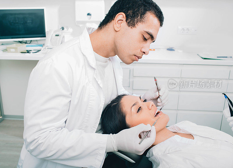 一位美国黑人牙医在牙科诊所给一位女病人检查牙齿。