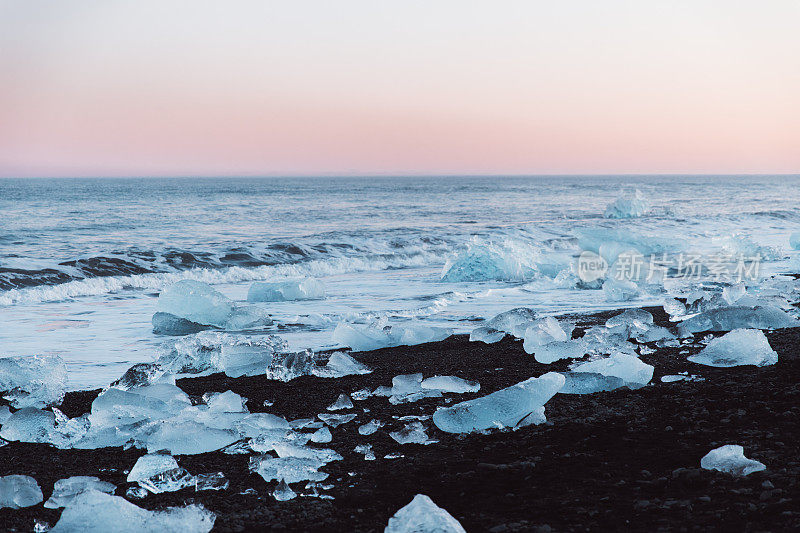冰岛冬季日落时美丽的黑色沙滩和冰山碎片