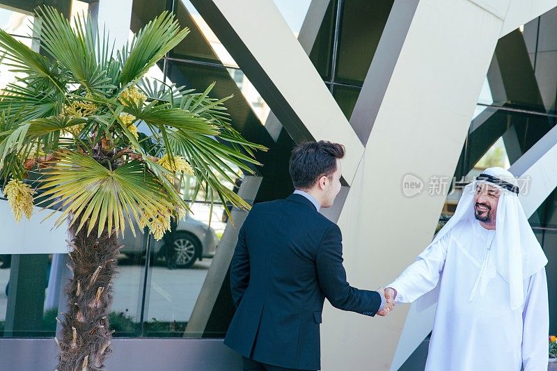 一位行政商人在户外与一位阿拉伯商人握手