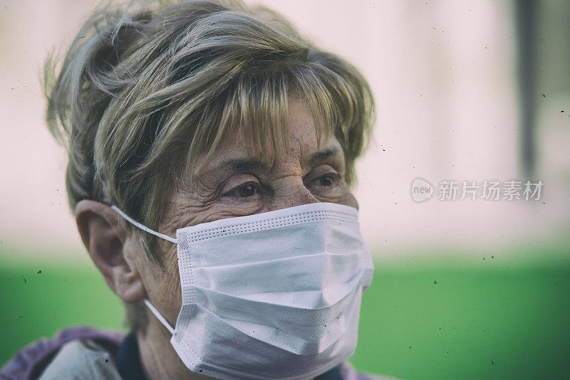 概念、疾病、病毒、过敏、空气污染。欧洲。一名老年妇女戴着防护面具参观这座城市