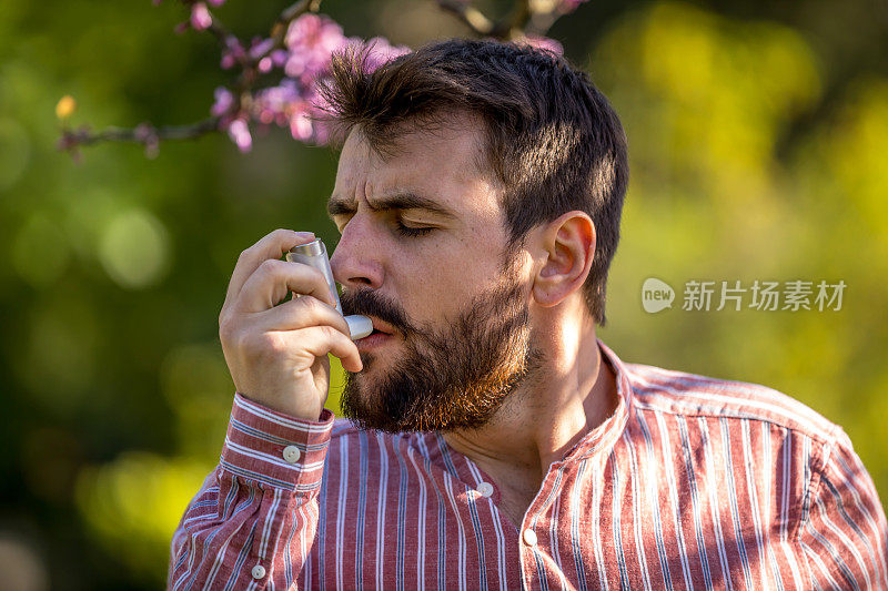 年轻男子在室外使用哮喘吸入器的肖像