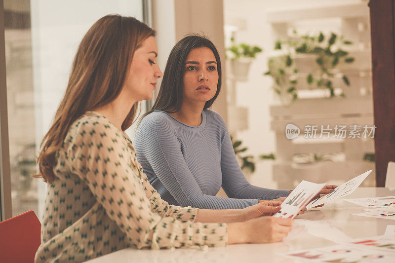 两位女企业家在一次商务会议上看文件