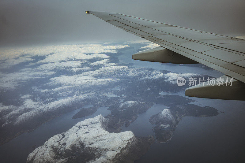 乘客从飞机上俯瞰挪威的北极峡湾，山上覆盖着积雪