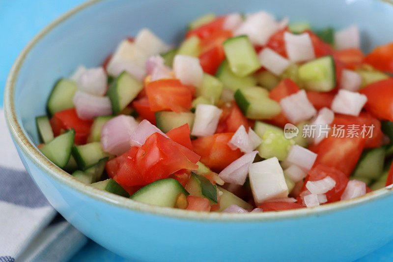 切碎的沙拉在蓝绿色的沙拉碗里，蔬菜包括，西红柿，黄瓜和洋葱，特写高空视图