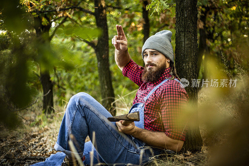 年轻人在砍柴时休息伐木工人森林里的一个伐木工人每天都在准备和砍柴