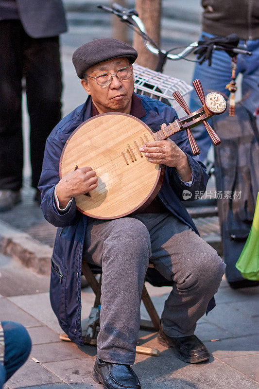 一位老人在北京的一个公园里弹奏中国传统乐器