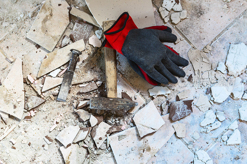 防护工作手套和锤子在破碎的瓷砖