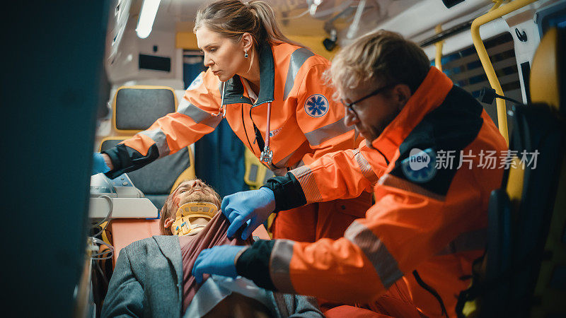 女性和男性EMS护理人员提供医疗帮助受伤的病人在去医疗保健医院的路上。急救助手在救护车上让这个人活了过来。