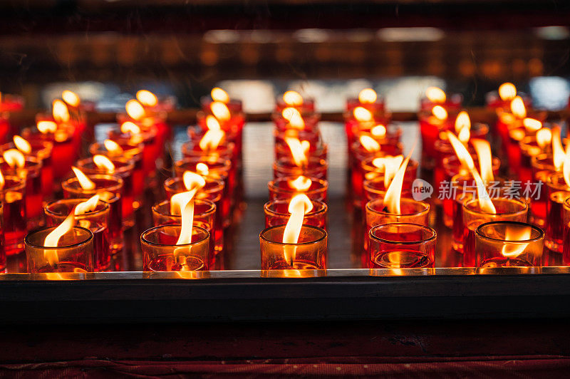 一排虔诚的红烛，玻璃中有火焰