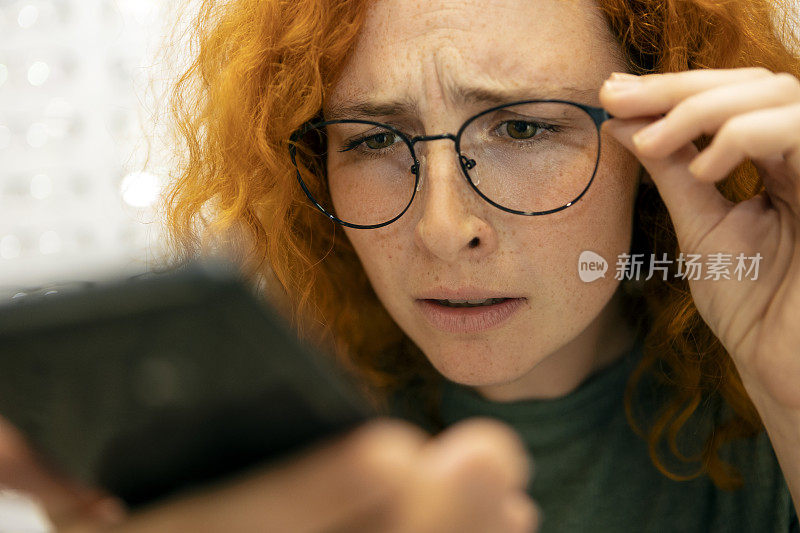 一位有视力问题的红发年轻女子试图阅读手机短信