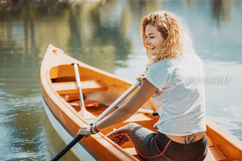 快乐美丽的女人在河边划独木舟